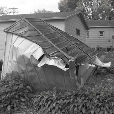 A tin shed damaged in a windstorm that was replaced by an Apex Shed