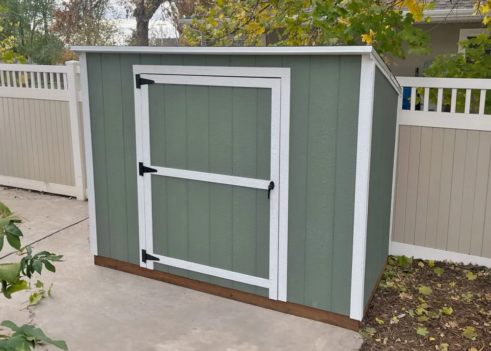 A 4 foot by 6 foot yard hutch shed in sage green with white trim